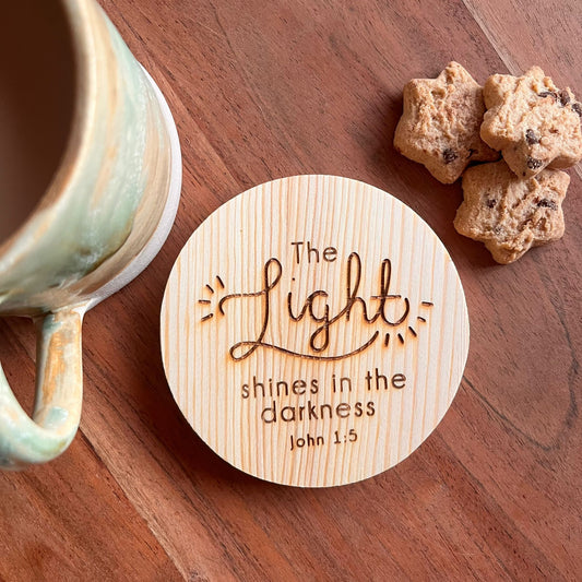 ‘The light shines in the darkness' wooden coaster