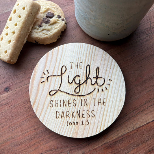‘The light shines in the darkness' wooden coaster
